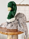Plush duck toy with a fluffy tail on a wooden surface