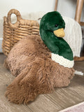 Plush toy duck on a wooden floor with a basket in the background