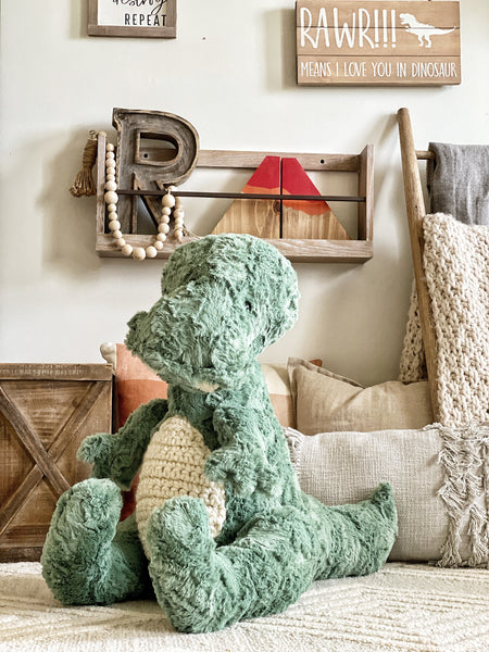 A large green T-Rex stuffed animal made by ClaraLoo in a dinosaur themed nursery.