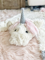 A plush unicorn rug made by ClaraLoo on the floor of a fantasy themed nursery. The unicorn rug features ultra soft fabric with a crocheted horn and ears.